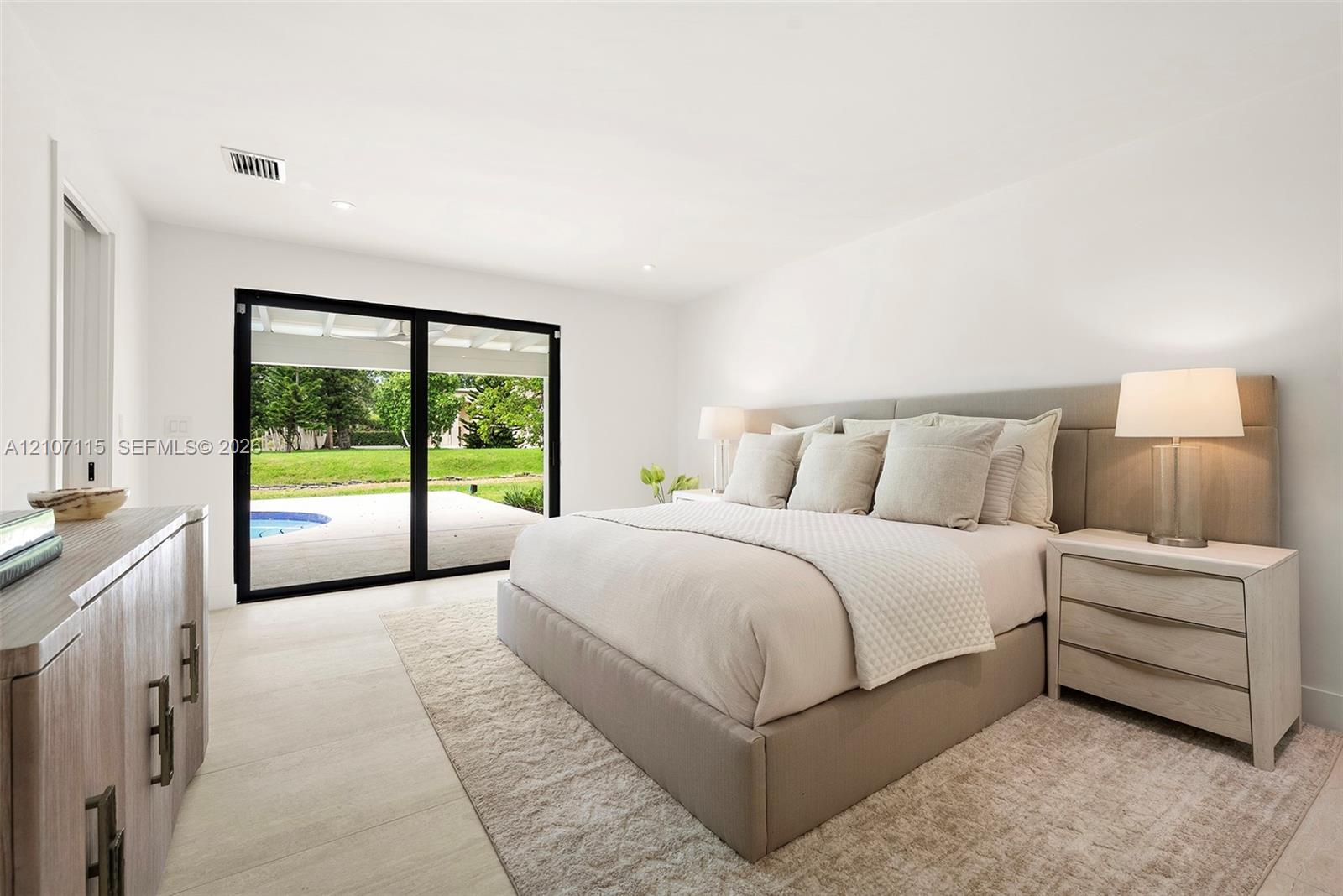 Spacious room featuring floor-to-ceiling sliding glass doors, neutral tile flooring, and recessed lighting