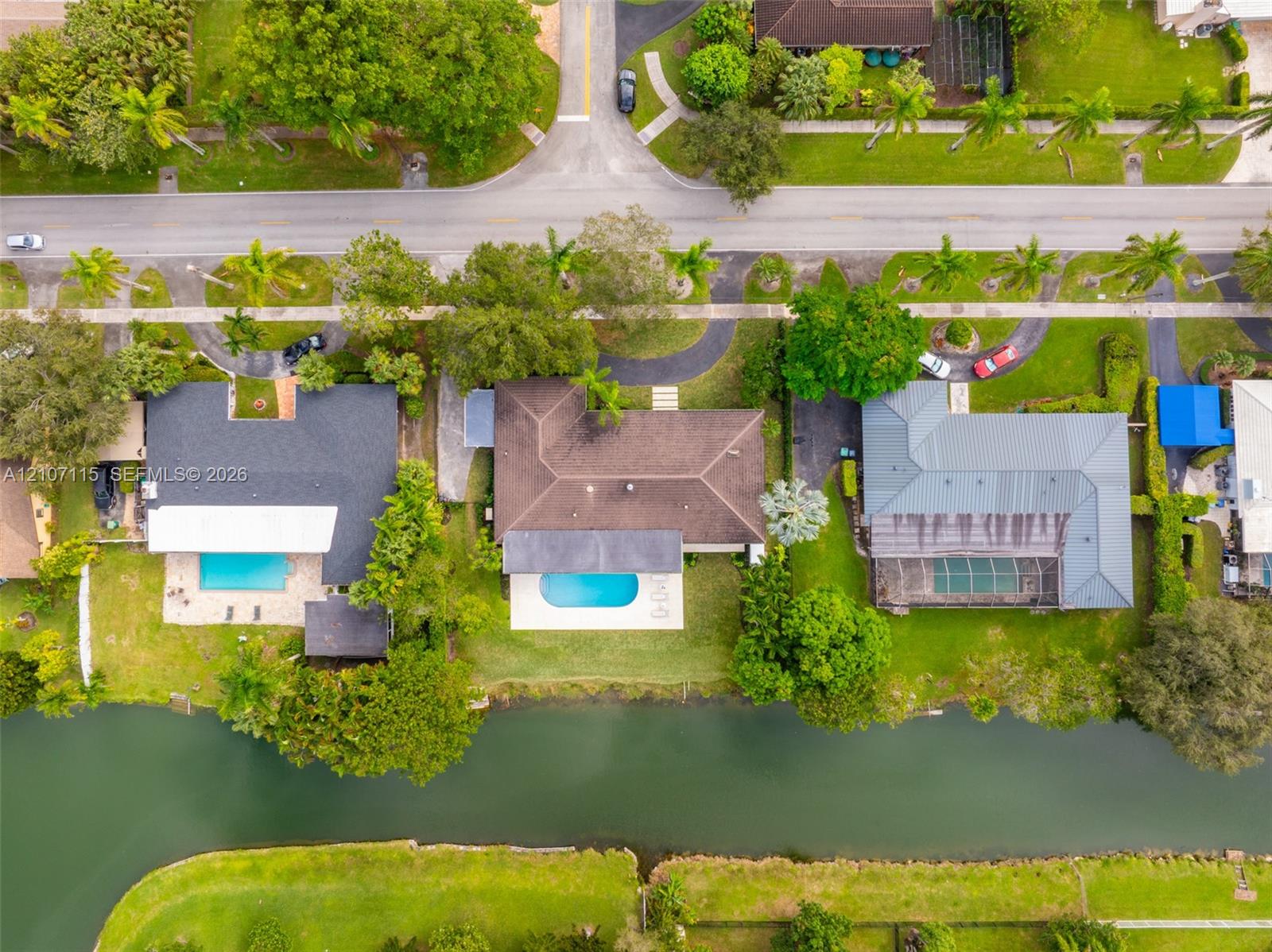 Aerial perspective of waterfront properties featuring swimming pools, lush landscaping, and direct canal access
