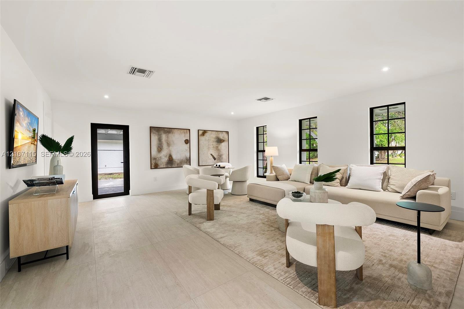 Open-concept living space featuring neutral wall-to-wall flooring, oversized windows with black frames, and recessed lighting