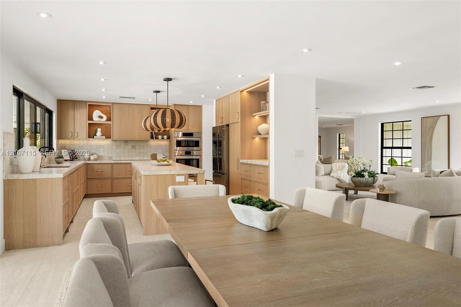 Custom wood cabinetry with integrated lighting, stone countertops, stainless steel built-in double ovens, recessed lighting, and large-format tile flooring