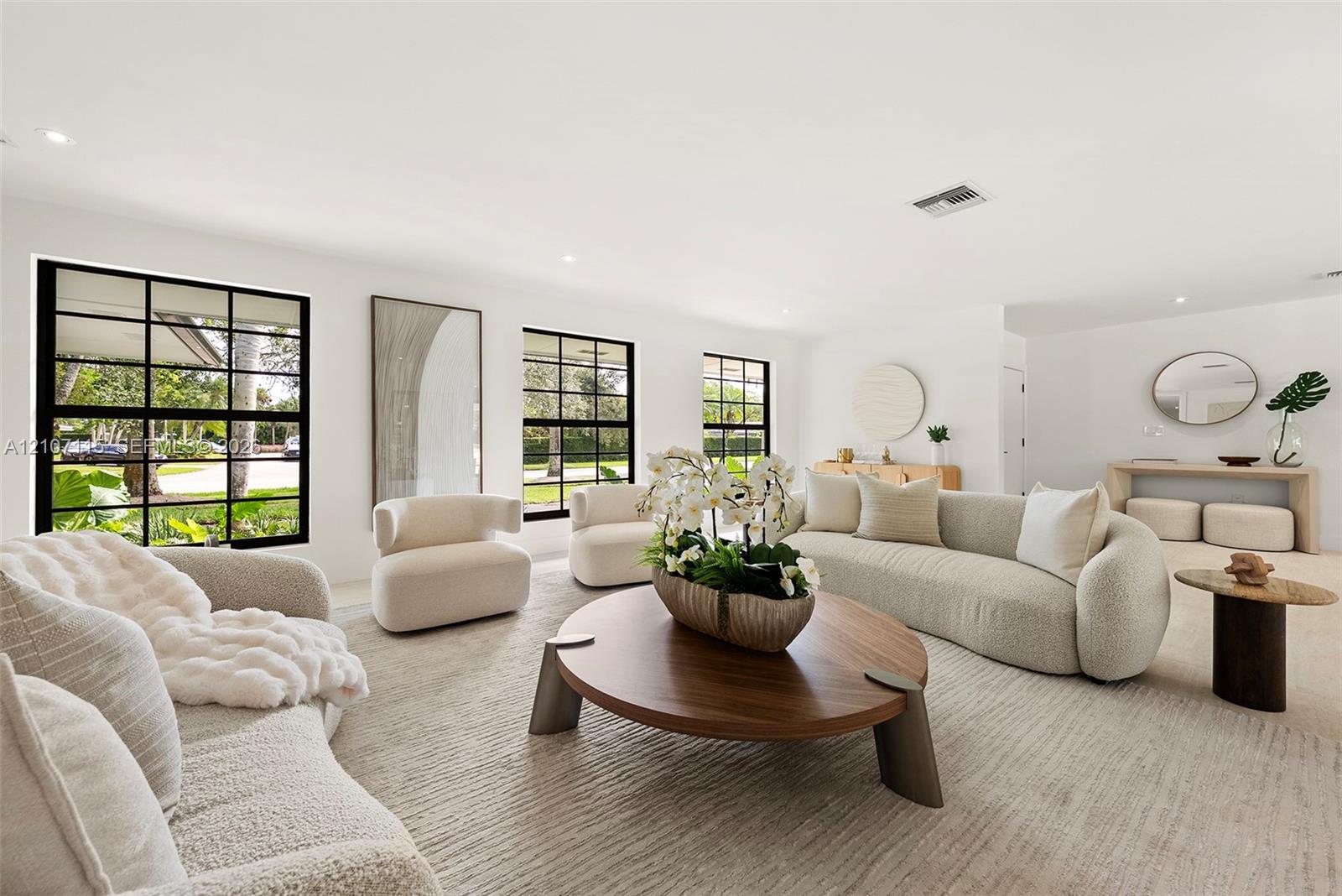Open-concept living space featuring expansive windows with black mullions, recessed ceiling lighting, and neutral-toned wall-to-wall carpeting