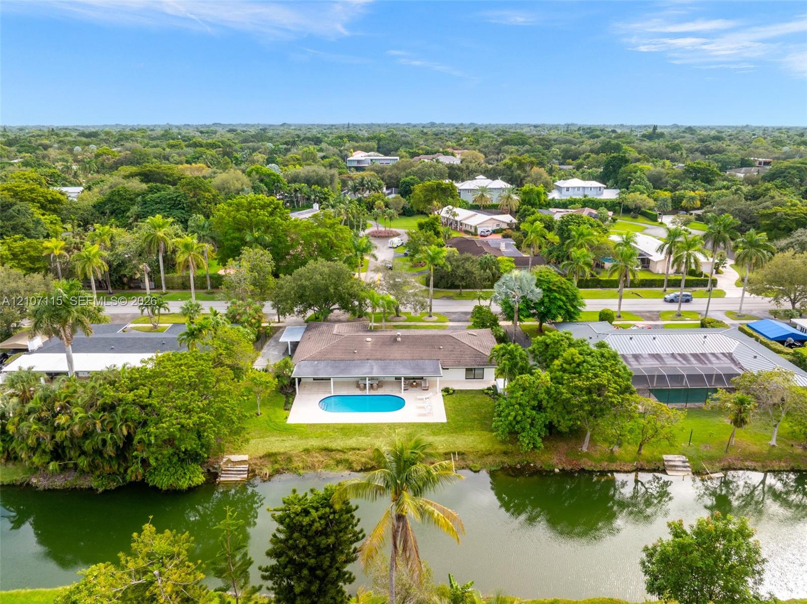Waterfront property featuring a swimming pool, covered concrete patio, and direct canal access with bulkhead