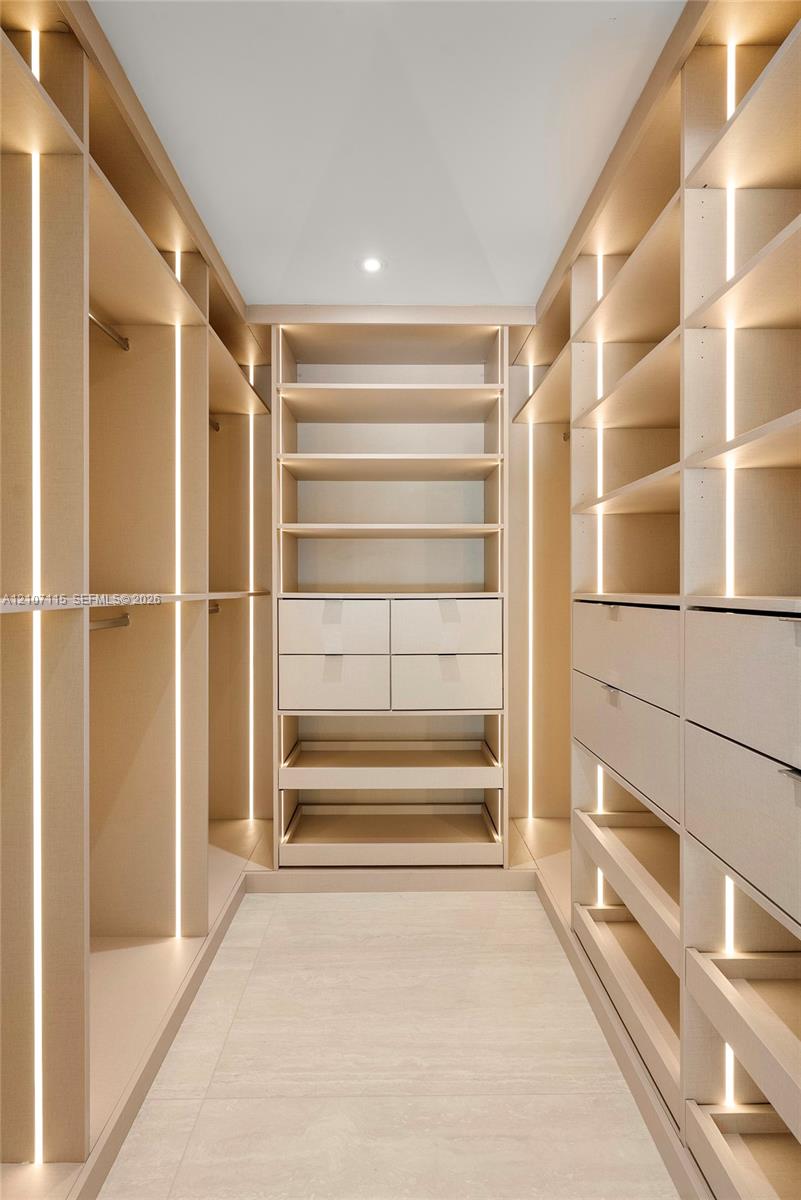 Custom walk-in closet featuring floor-to-ceiling built-in cabinetry, integrated vertical LED strip lighting, modular shelving, and multi-drawer storage units