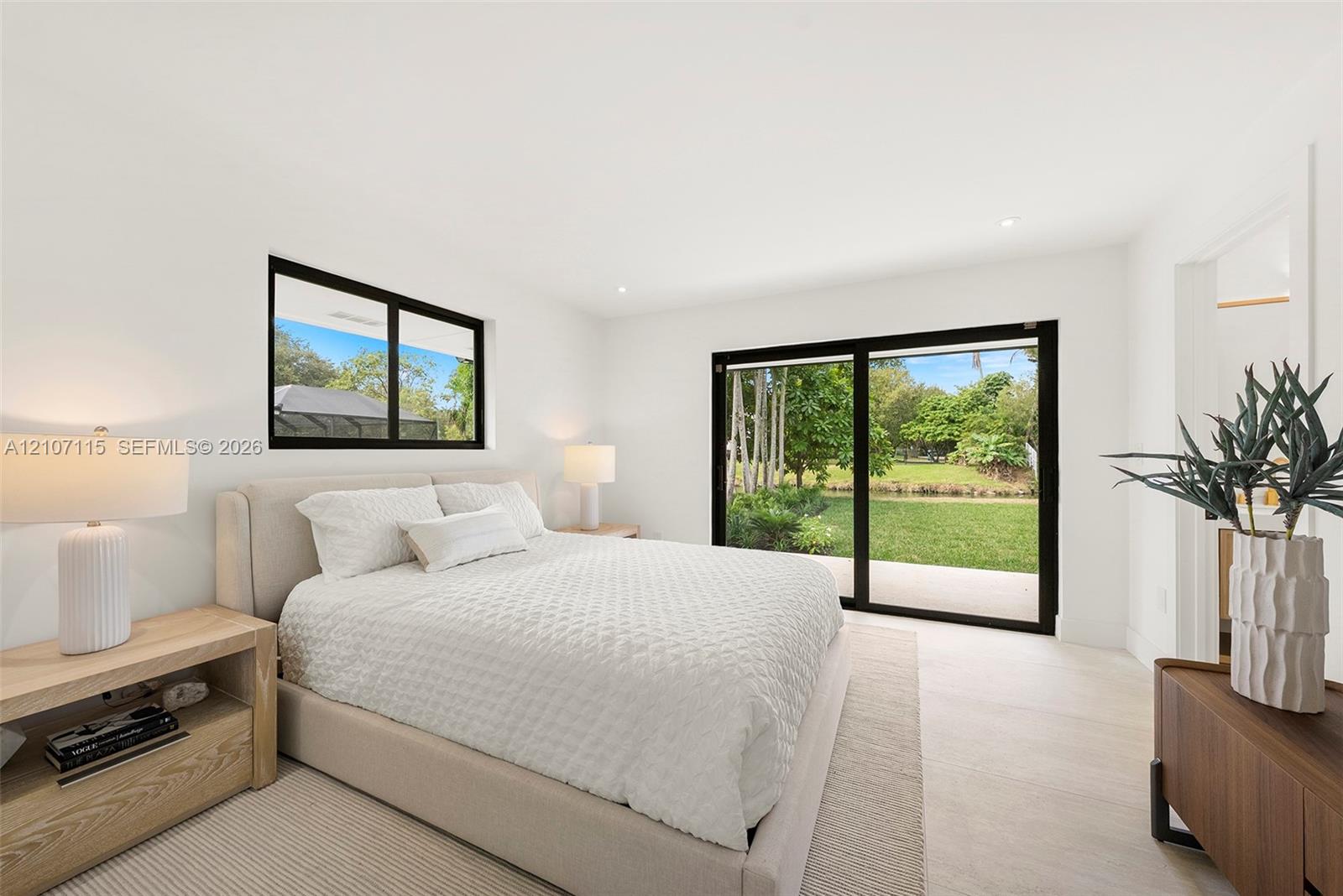 Suite Bedroom 1 ,Bright interior featuring neutral walls, large sliding glass doors, black-framed windows, and light-toned flooring