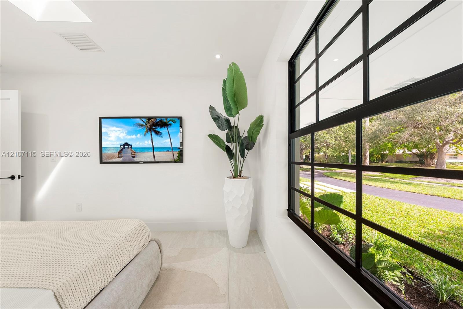Large grid-pattern windows with black frames, light-toned flooring, recessed lighting, and a skylight