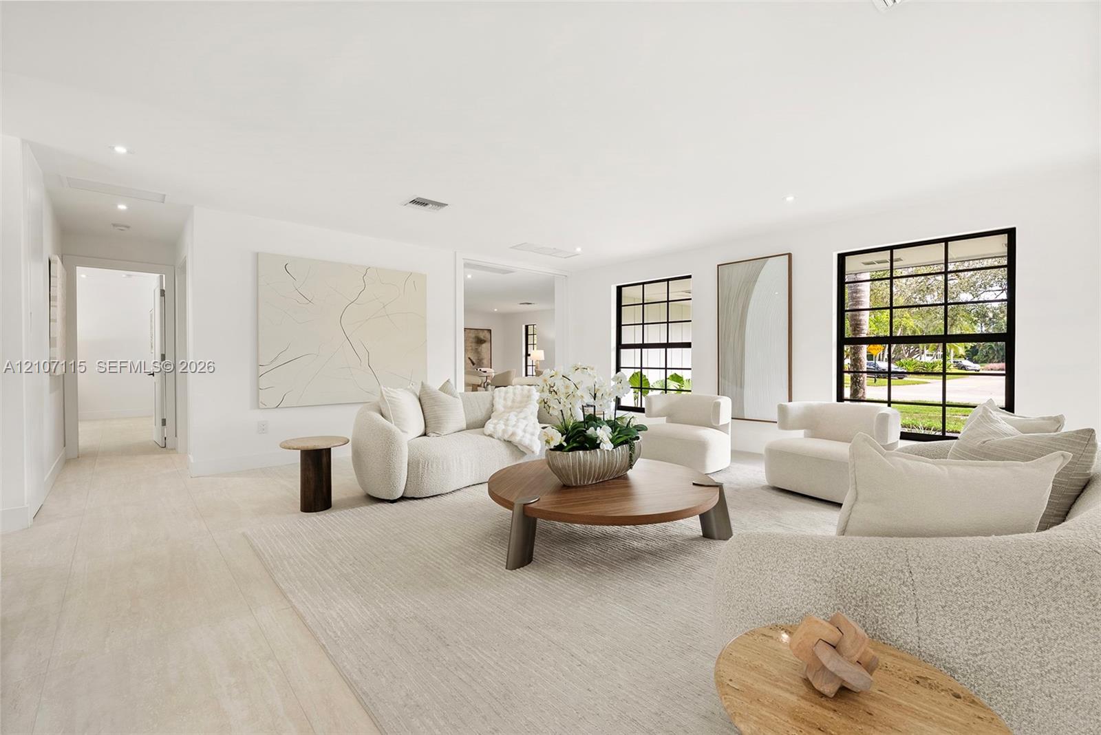 Bright interior space featuring light stone-finish tile flooring, recessed ceiling lighting, and large windows with black metal muntins