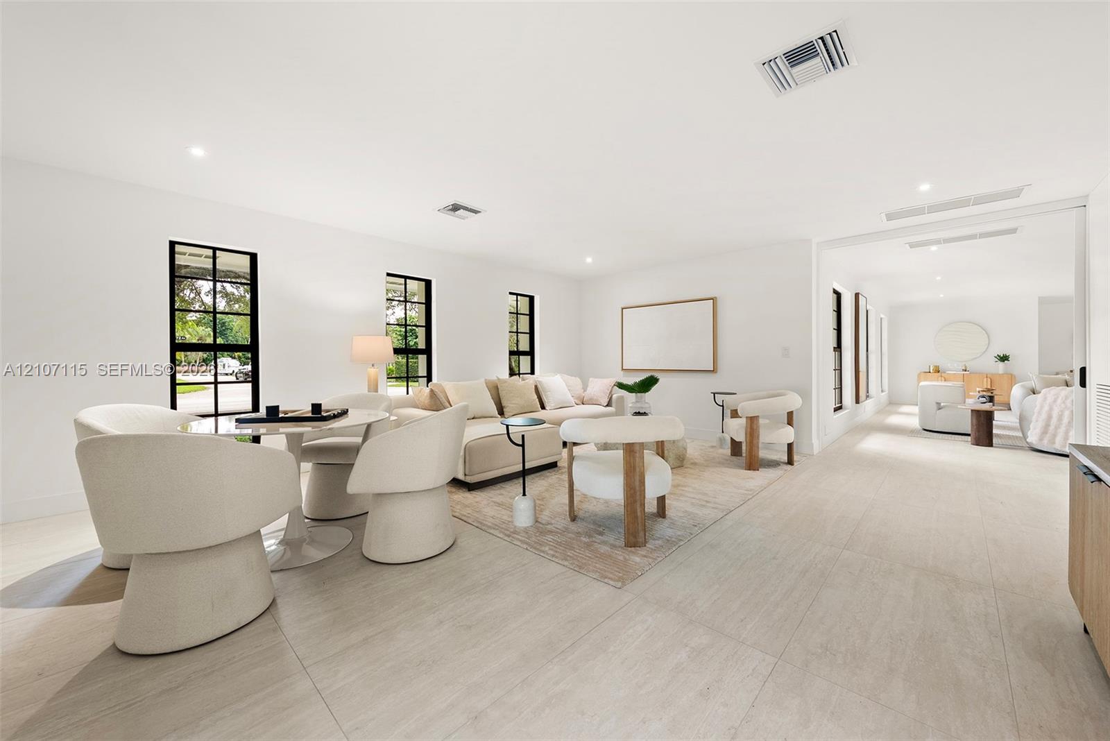 Open-concept interior featuring large-format tile flooring, recessed lighting, and black-trimmed multi-pane windows