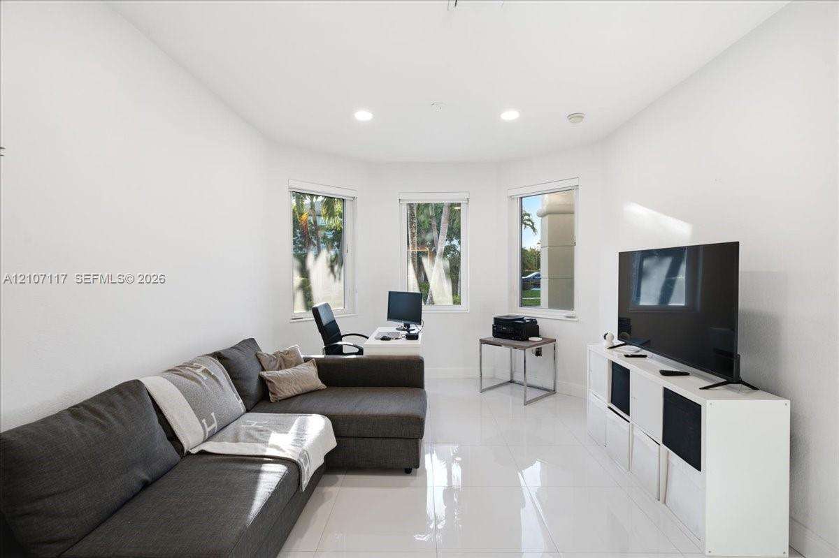 Bright room featuring glossy tile flooring, three large windows, and recessed lighting