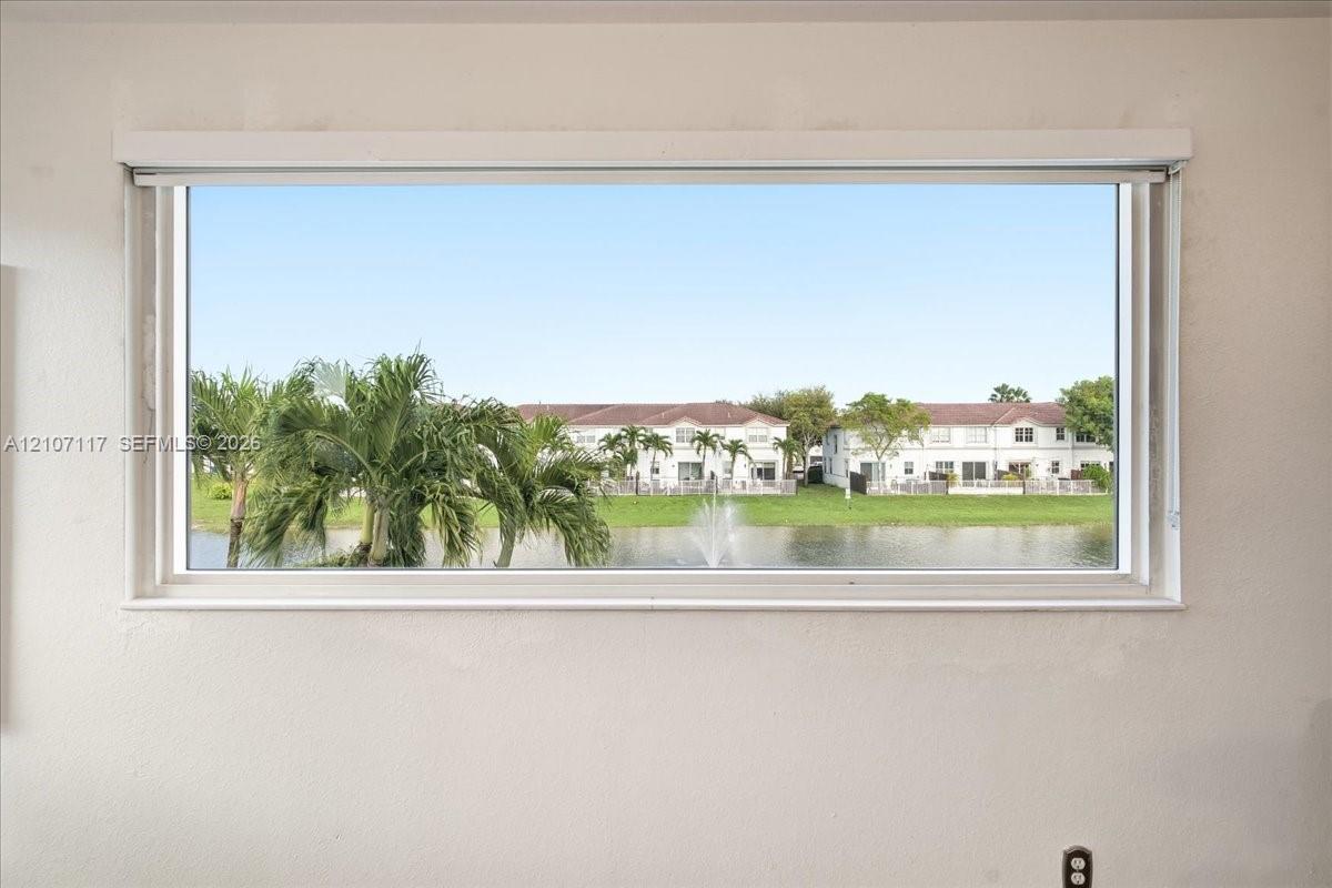 Horizontal window frame featuring a water feature, palm trees, and residential scenery