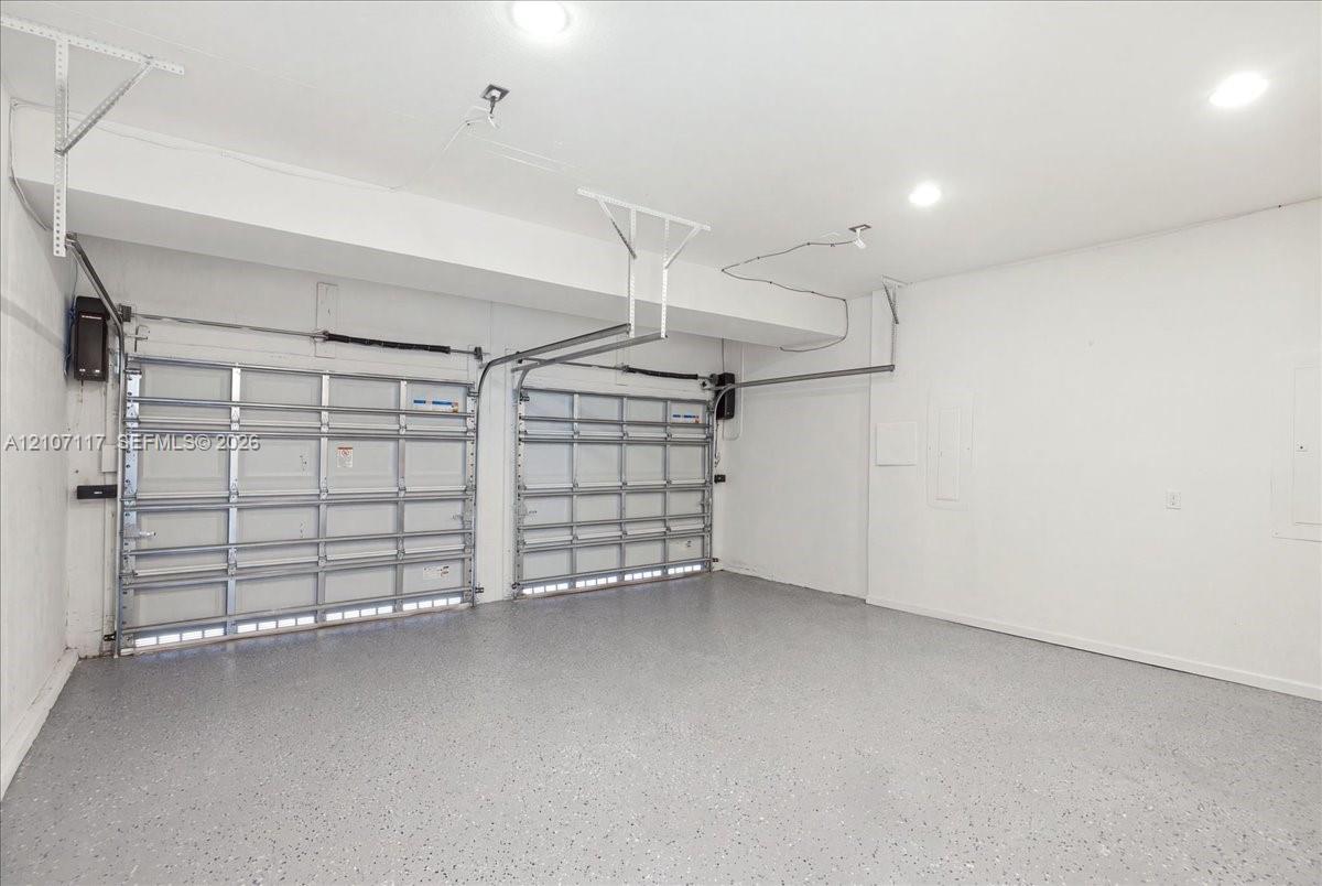 Two-car garage featuring finished epoxy flooring, white walls, and recessed lighting