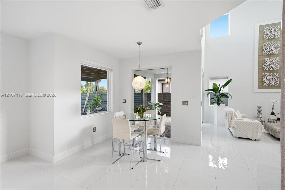 Open-concept space featuring polished tile flooring, soaring vaulted ceilings, expansive windows, and a modern spherical pendant light fixture