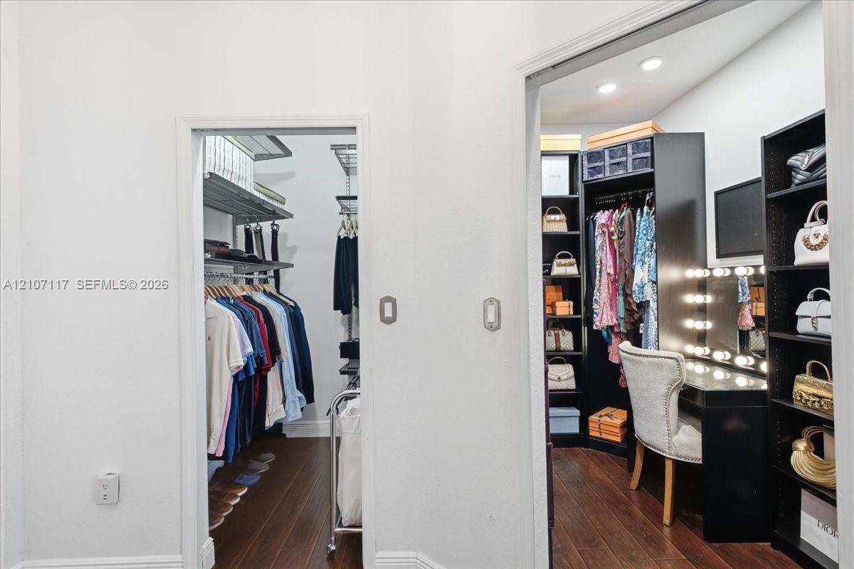 Walk-in storage spaces featuring dark wood-finish flooring, built-in shelving units, integrated task lighting, and a built-in vanity