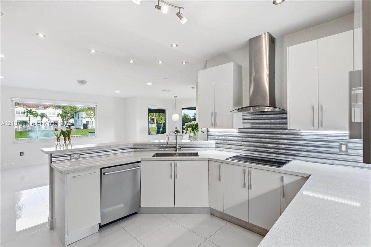 Contemporary kitchen featuring flat-panel white cabinetry, light-toned countertops, a textured metal backsplash, stainless steel appliances, and large-format floor tiling