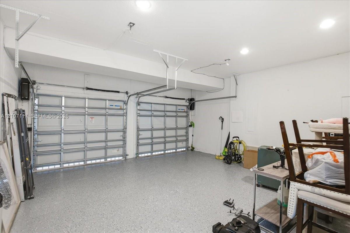 Two-car garage featuring dual overhead metal doors, neutral wall finish, recessed lighting, and durable flecked-epoxy flooring