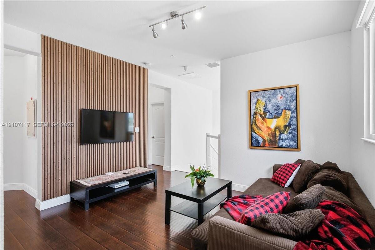 Vertical wood slat accent wall, dark-toned wood-finish flooring, and adjustable multi-bulb track lighting