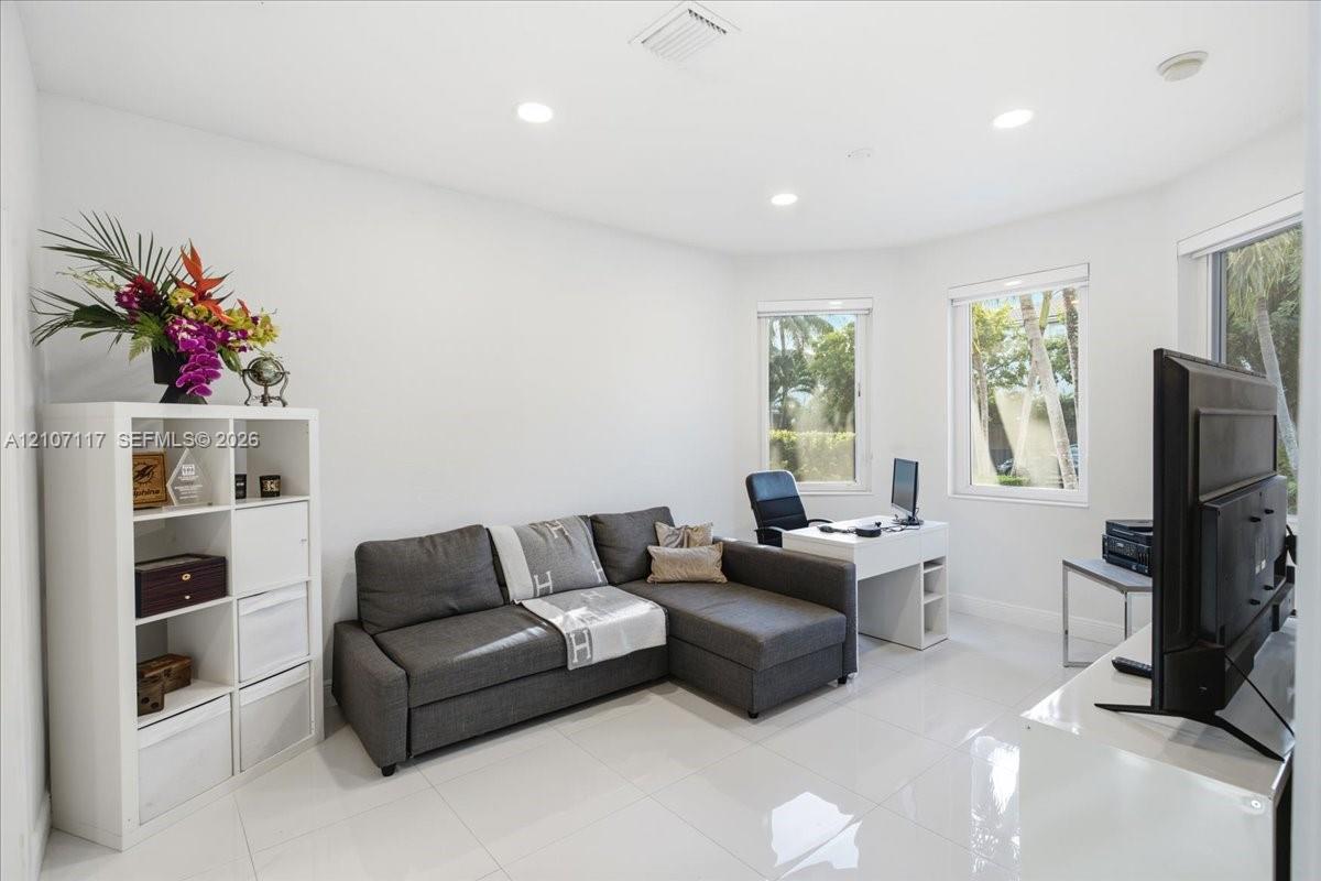 Neutral-toned interior featuring large-format tile flooring, recessed ceiling lighting, and expansive bay windows