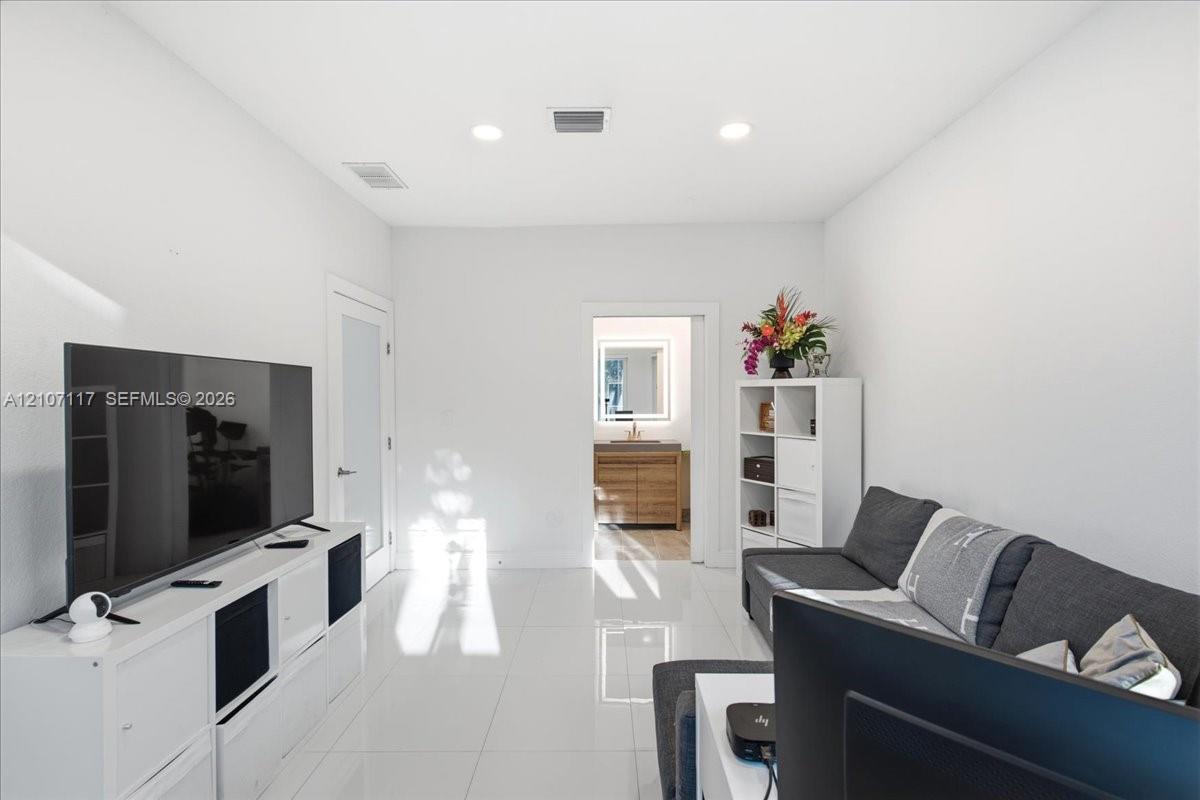 High-gloss porcelain tile flooring, recessed ceiling lighting, and a frosted glass-panel interior door