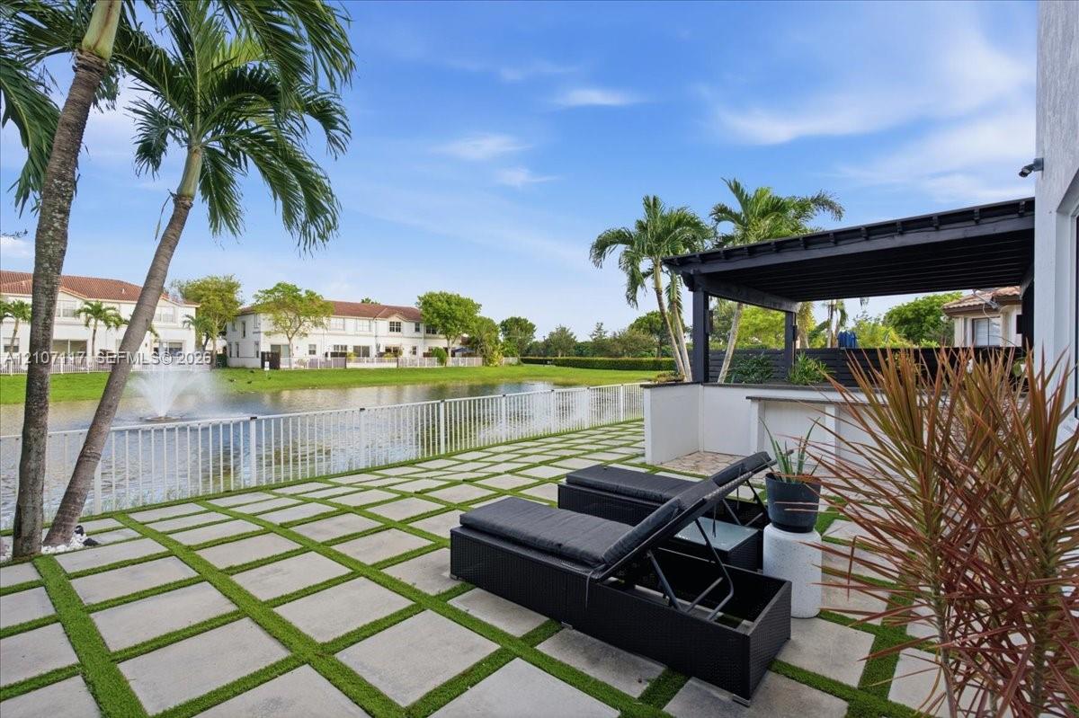 Rear patio featuring concrete pavers with grass inlay, a built-in outdoor bar, and a covered pergola