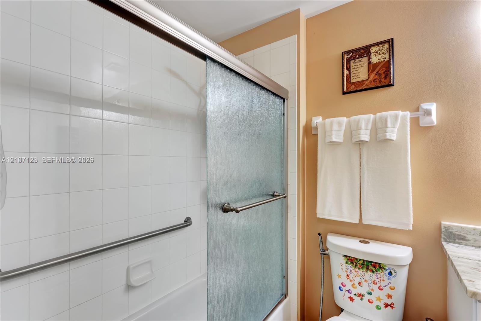 Full-height tiled shower surround featuring a sliding glass door and integrated metal safety grab bar