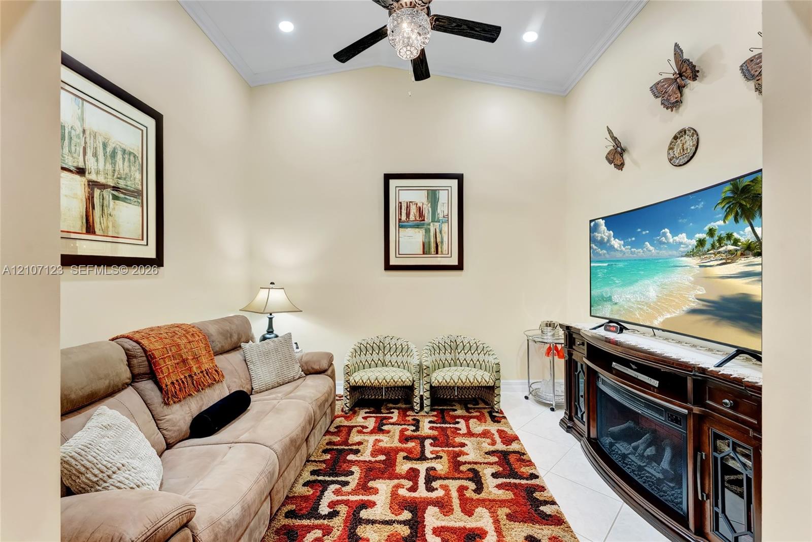 Vaulted ceiling featuring a ceiling fan with integrated lighting, recessed lighting, crown molding, and large-format tile flooring
