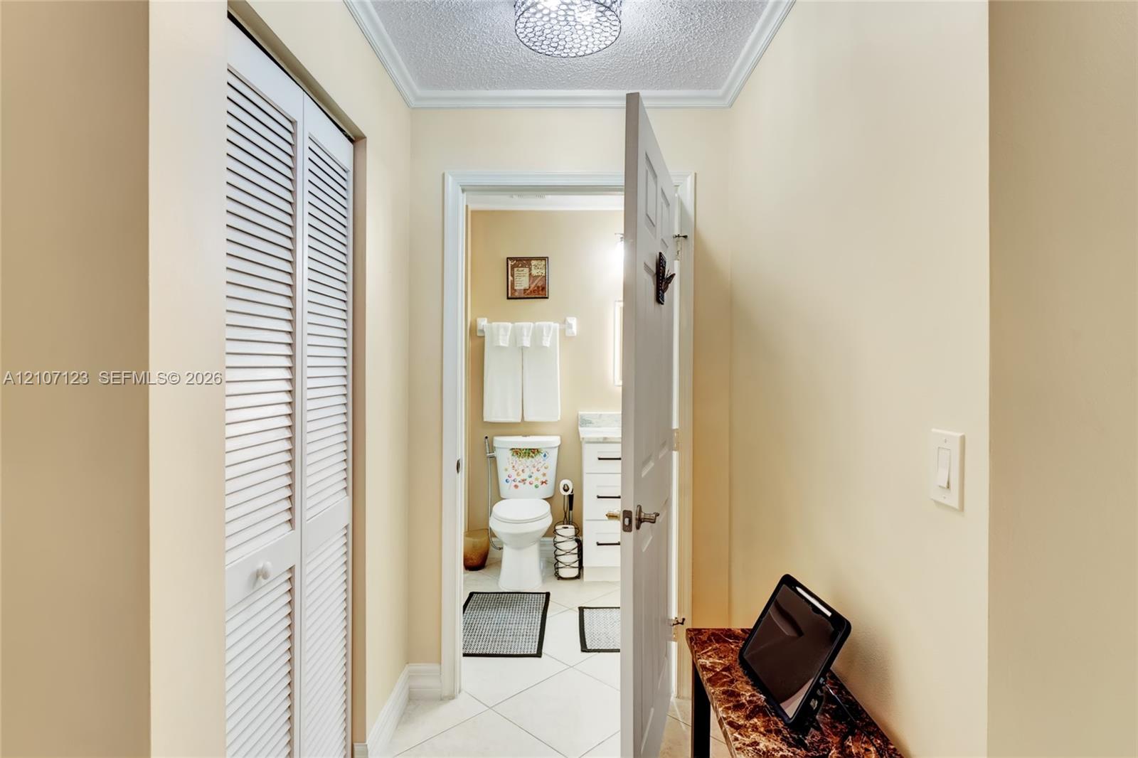 White louvered closet doors, neutral wall finish, and ceiling-mounted flush light fixture