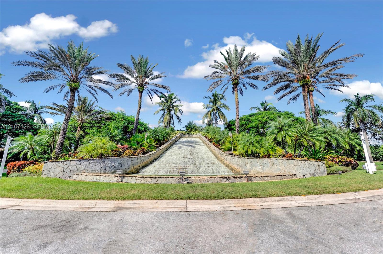 Stone-clad water feature surrounded by lush tropical landscaping and mature palm trees