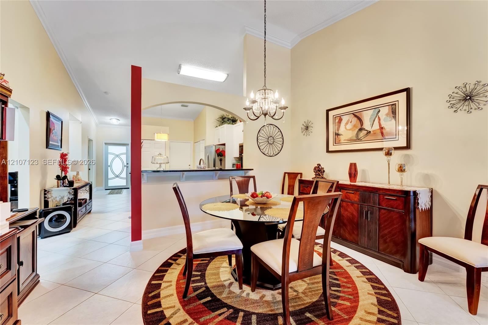 Dining area featuring vaulted ceilings, a decorative chandelier, tile flooring, and a pass-through arched opening with a breakfast bar