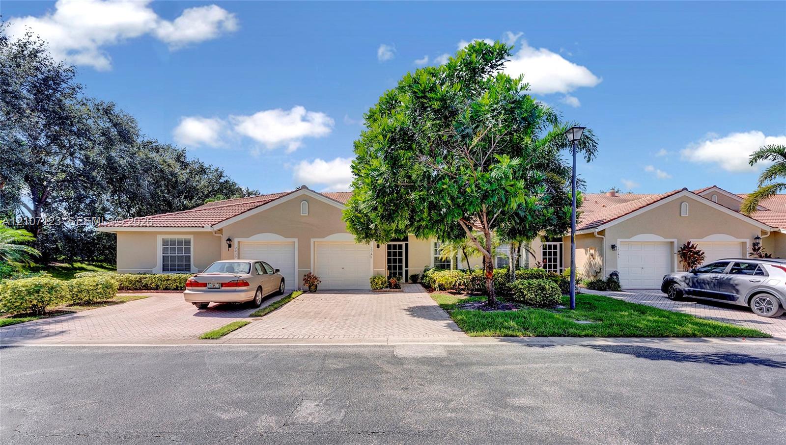 Single-story residence featuring a tile roof, dual-bay garages with paneled doors, and paved driveways