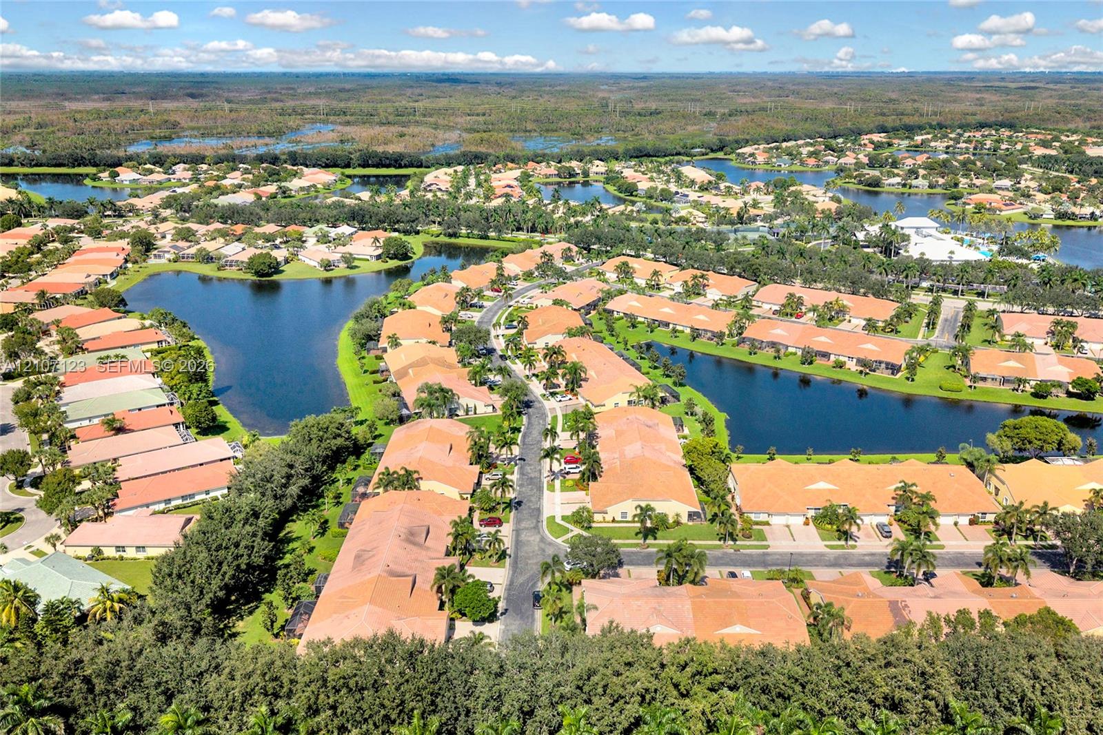 Aerial perspective featuring clustered residential structures with clay-tile roofing, expansive interconnected water features, and mature landscaping