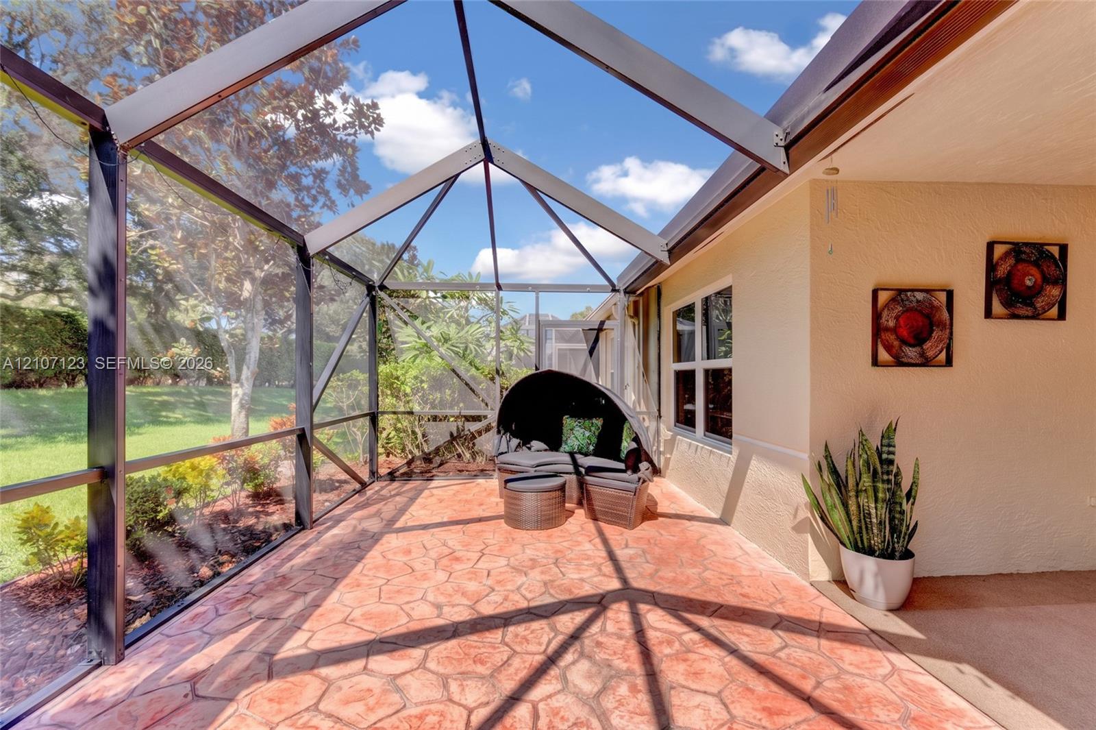 Screened-in lanai featuring a vaulted ceiling and textured paver flooring