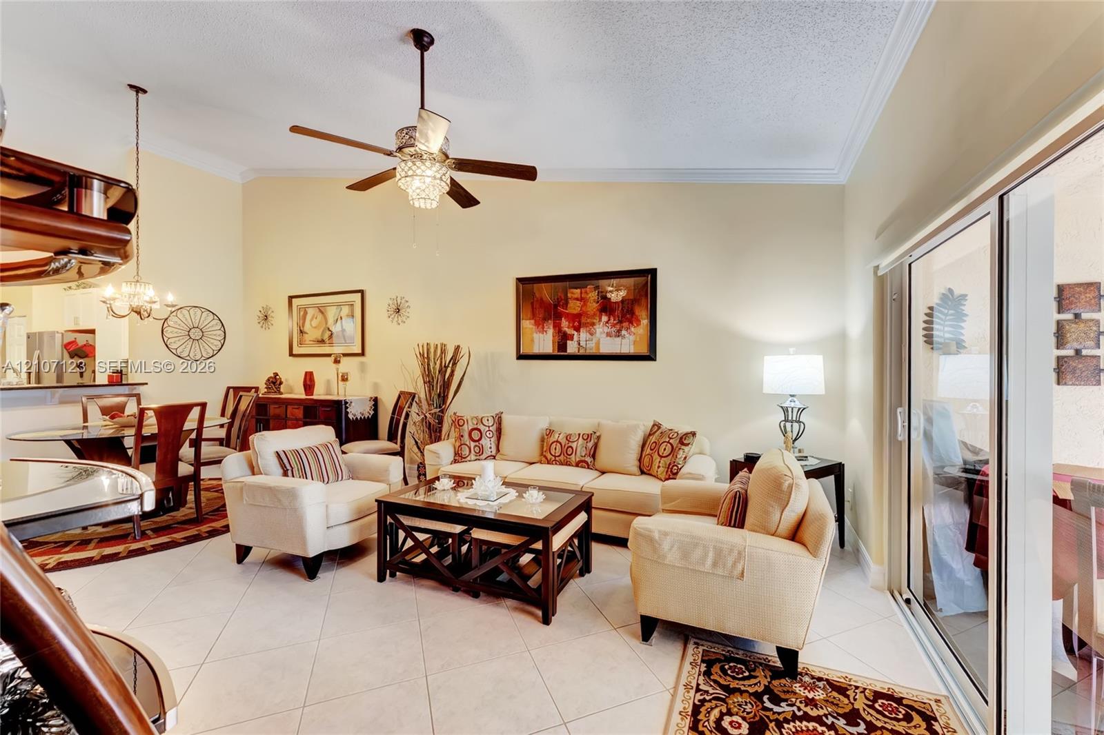 Vaulted ceilings with a central crystal-accented ceiling fan, ceramic tile flooring, and large sliding glass doors