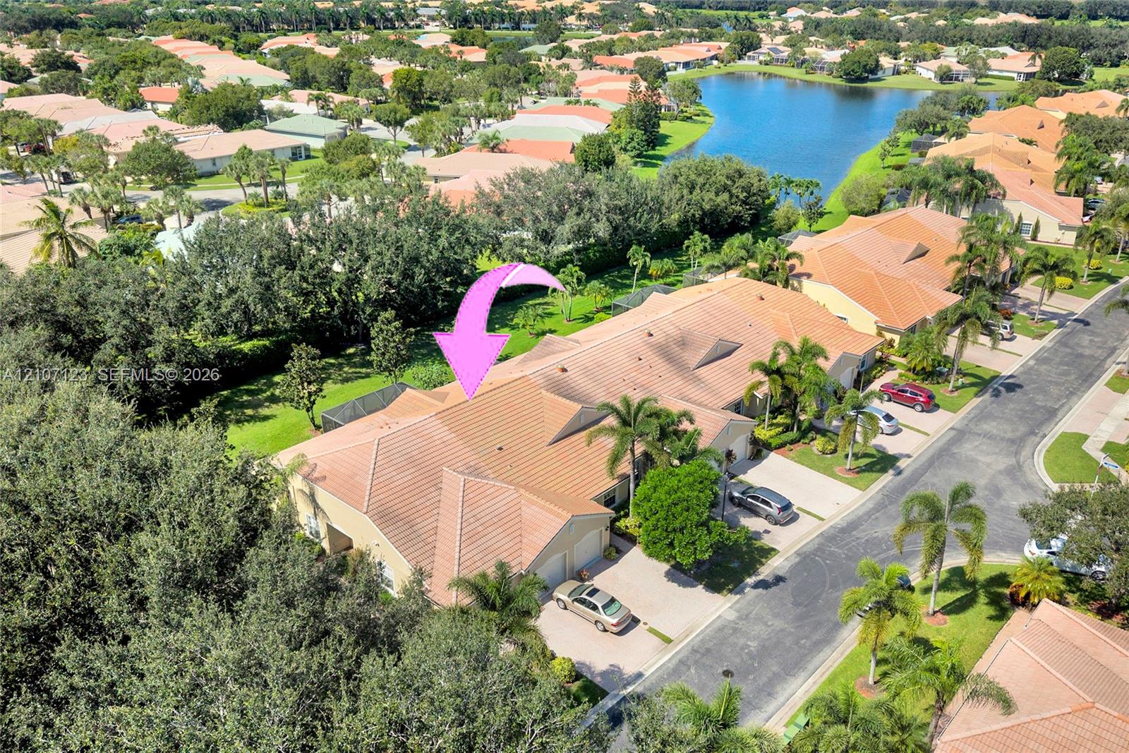 Aerial perspective featuring a tile roof, multi-car garage, and concrete driveway, situated on a lot with mature landscaping