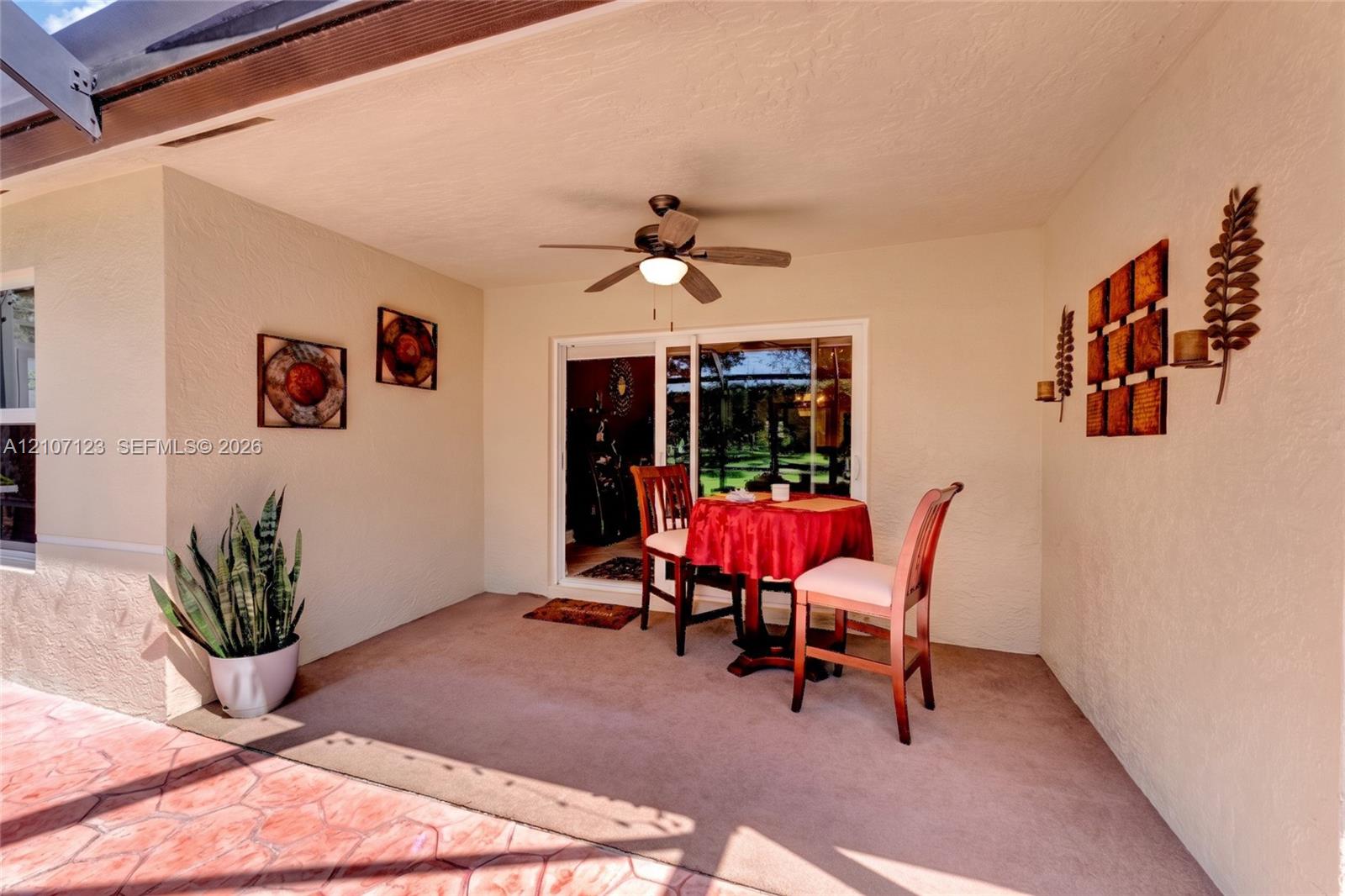 Covered patio featuring a stained concrete floor, textured stucco walls, and a ceiling-mounted paddle fan