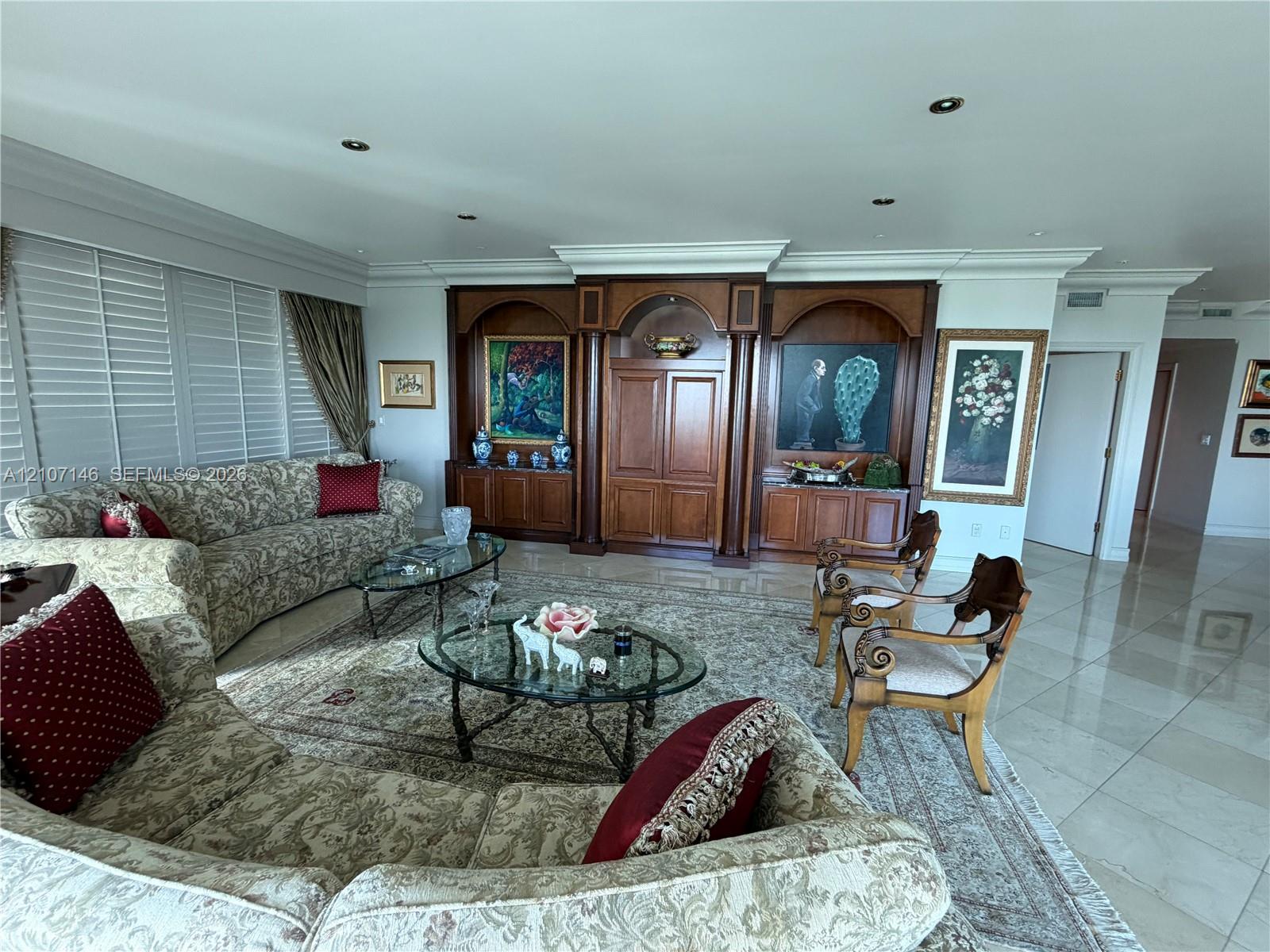 Custom built-in wood cabinetry, integrated crown molding, recessed lighting, and polished stone-finish flooring