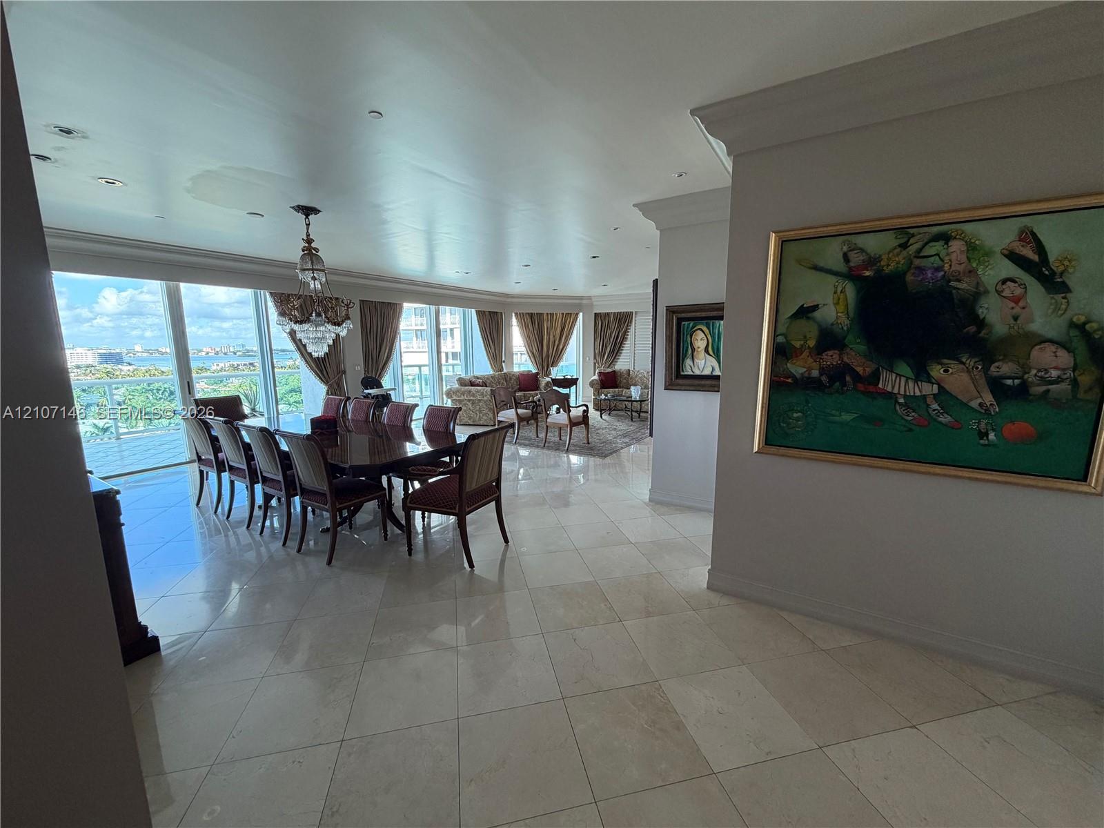 Polished stone flooring, recessed ceiling lighting, crystal chandelier, and floor-to-ceiling glass sliding doors opening to an exterior balcony