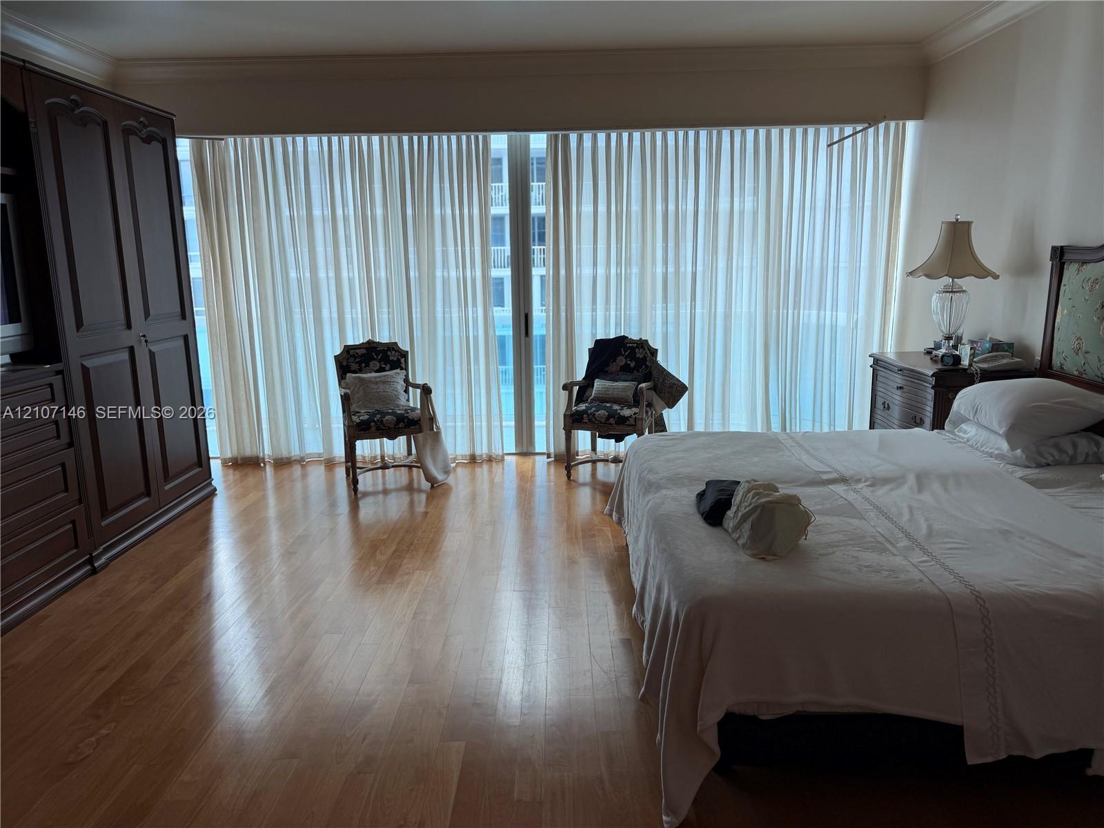 Floor-to-ceiling glass sliding doors with drapery, wood-finish flooring, and crown molding
