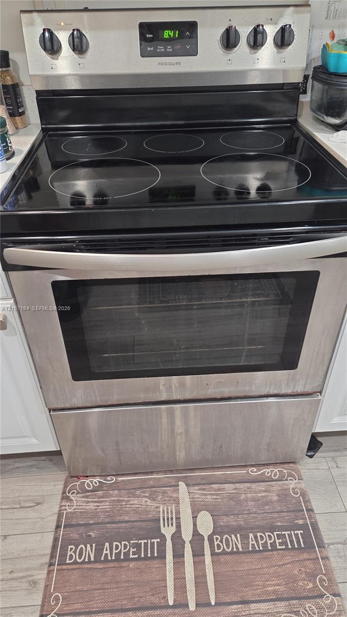 Stainless steel freestanding electric range with a glass cooktop, digital control panel, and full-width oven handle