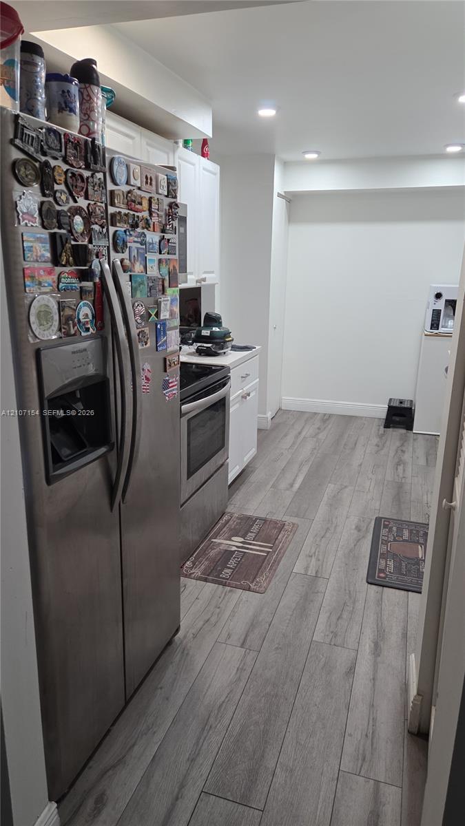 Kitchen featuring stainless steel appliances, white cabinetry, and wood-finish flooring with recessed lighting