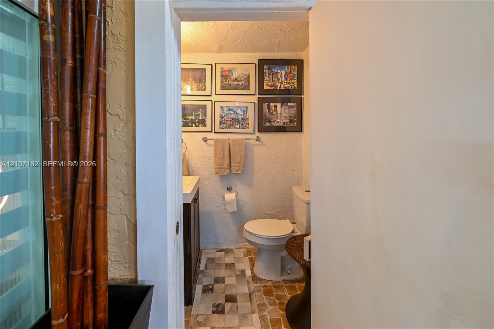 Restroom featuring a wall-mounted metal towel bar, dark-finish cabinetry, and square multi-tone tile flooring