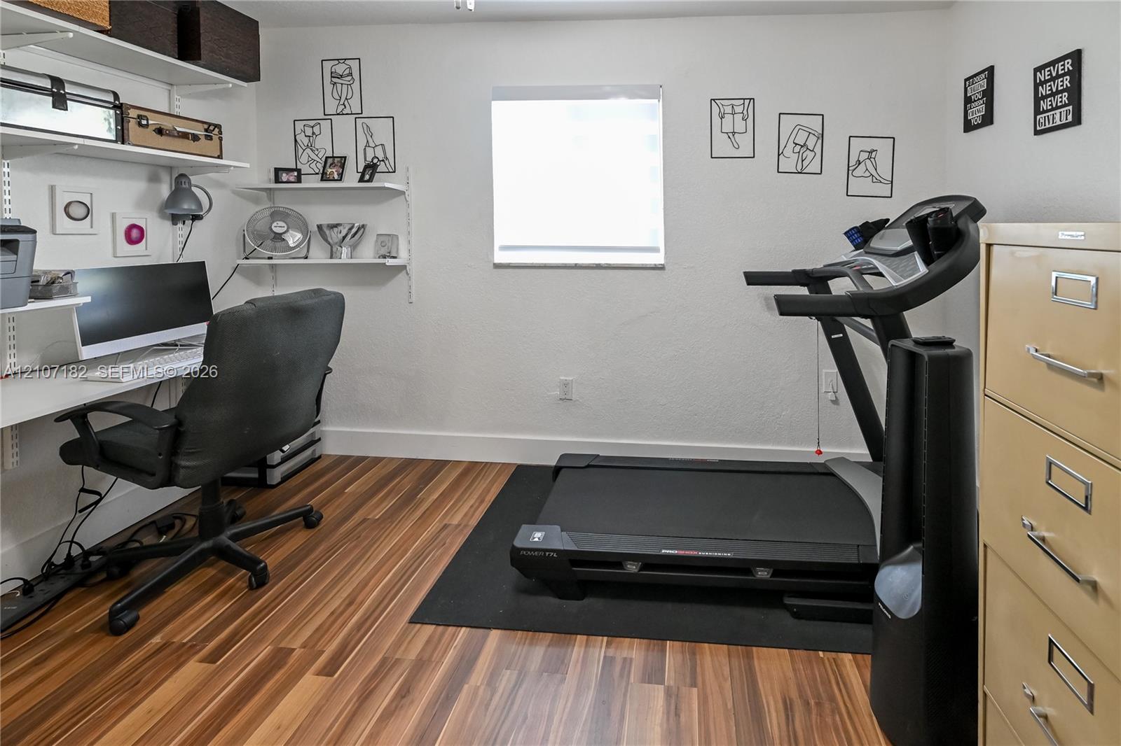 Room featuring wood-finish flooring, built-in white wall shelving, and a centrally located window