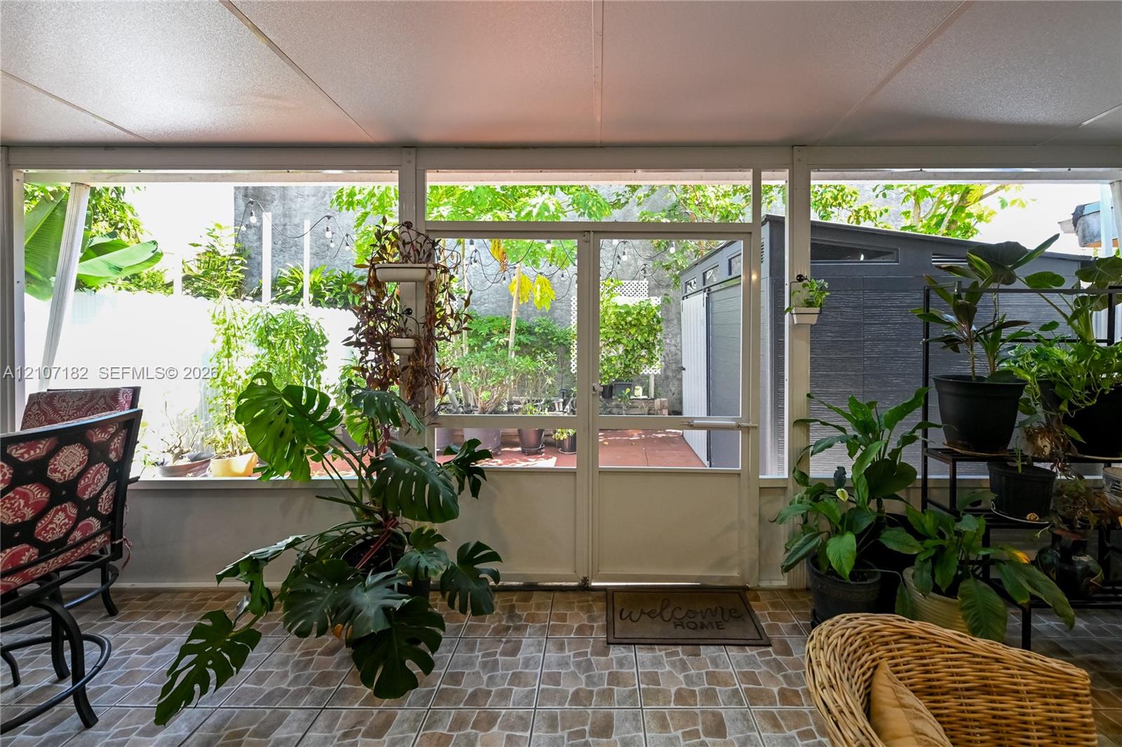 Enclosed patio featuring floor-to-ceiling screen panels, patterned tile flooring, and a glass-paneled entry door