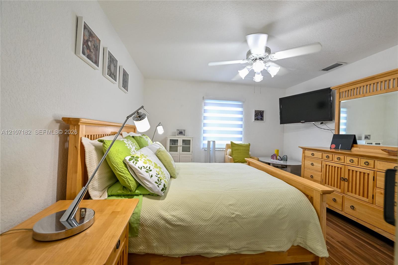 Room featuring wood-finish flooring, a ceiling fan with integrated lighting, and horizontal window blinds