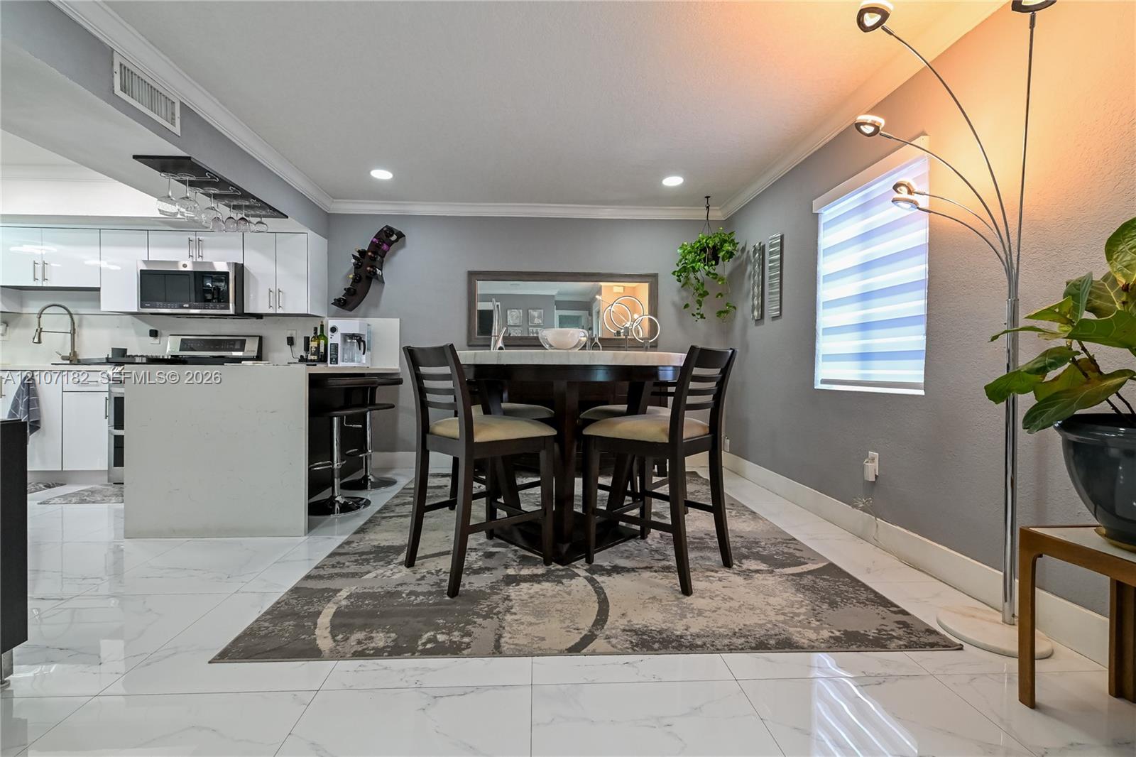 Polished stone-finish tile flooring, white gloss cabinetry, quartz countertop, recessed ceiling lighting, and horizontal tiered window shades Polished stone-finish tile flooring, white gloss cabinetry, quartz countertop, recessed ceiling lighting, and horizontal tiered window shades