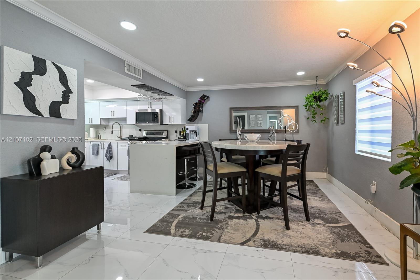 Large-format tile flooring, recessed lighting, crown molding, and white cabinetry with a built-in wine rack Large-format tile flooring, recessed lighting, crown molding, and white cabinetry with a built-in wine rack