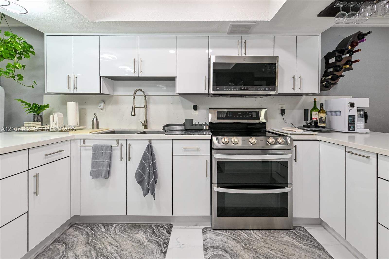 Kitchen featuring high-gloss white cabinetry, white countertops, stainless steel dual-oven range, over-the-range microwave, and a gooseneck faucet
