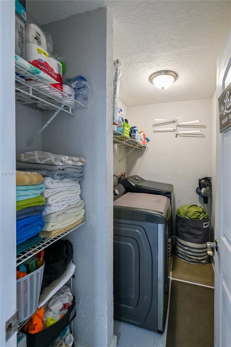 Laundry space featuring built-in wire shelving and a flush-mount ceiling light fixture Laundry space featuring built-in wire shelving and a flush-mount ceiling light fixture