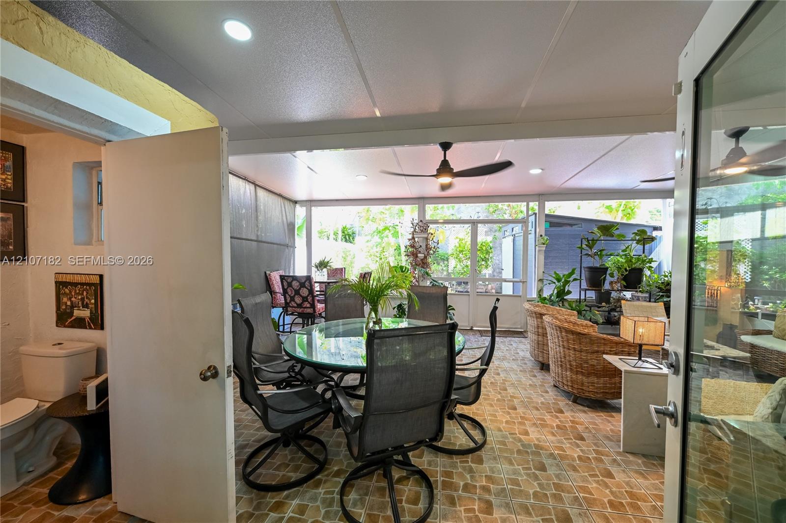 Enclosed patio featuring stone-patterned tile flooring, recessed lighting, and a ceiling fan