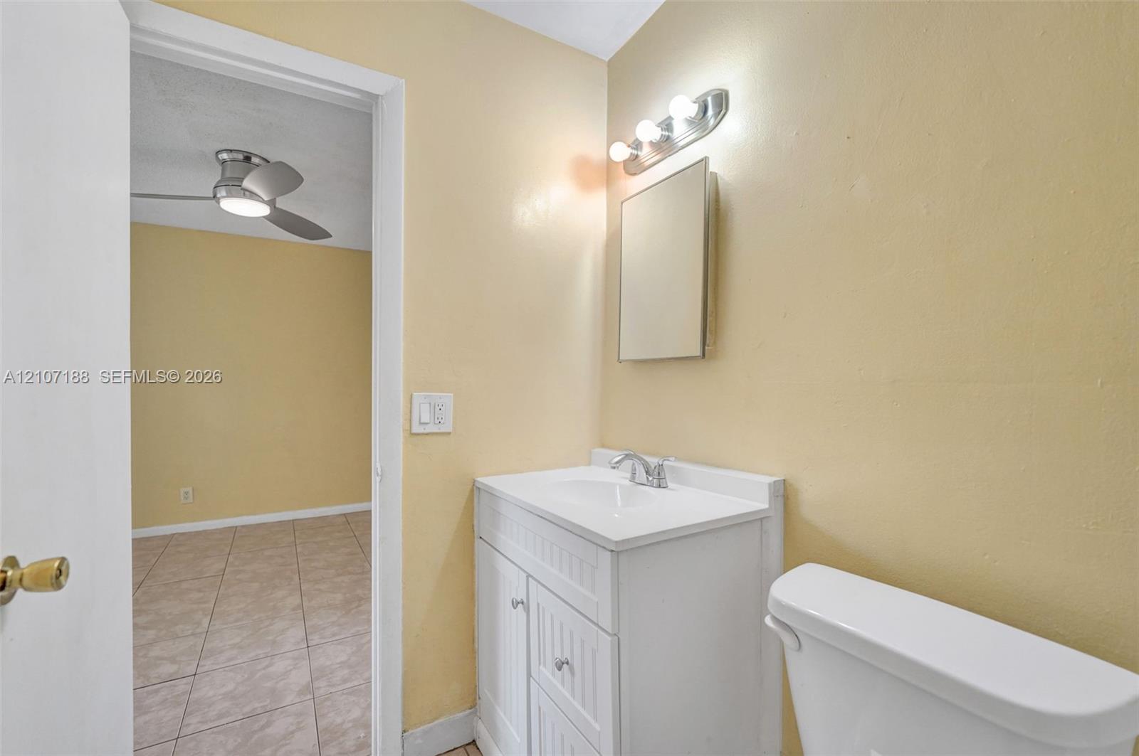 Bathroom featuring a white vanity cabinet with beadboard paneling, an integrated white sink, a chrome faucet, a wall-mounted medicine cabinet, and a multi-bulb vanity light fixture