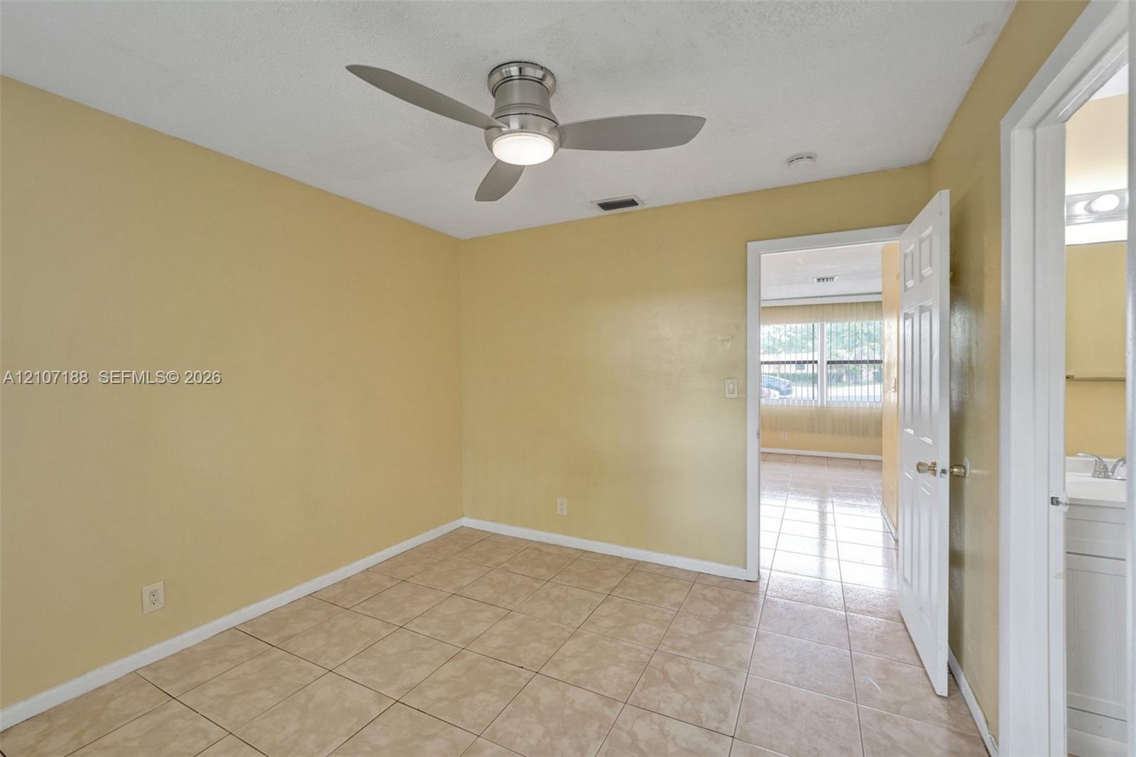 Room featuring neutral wall paint, tile flooring, and a modern brushed-nickel ceiling fan with integrated lighting