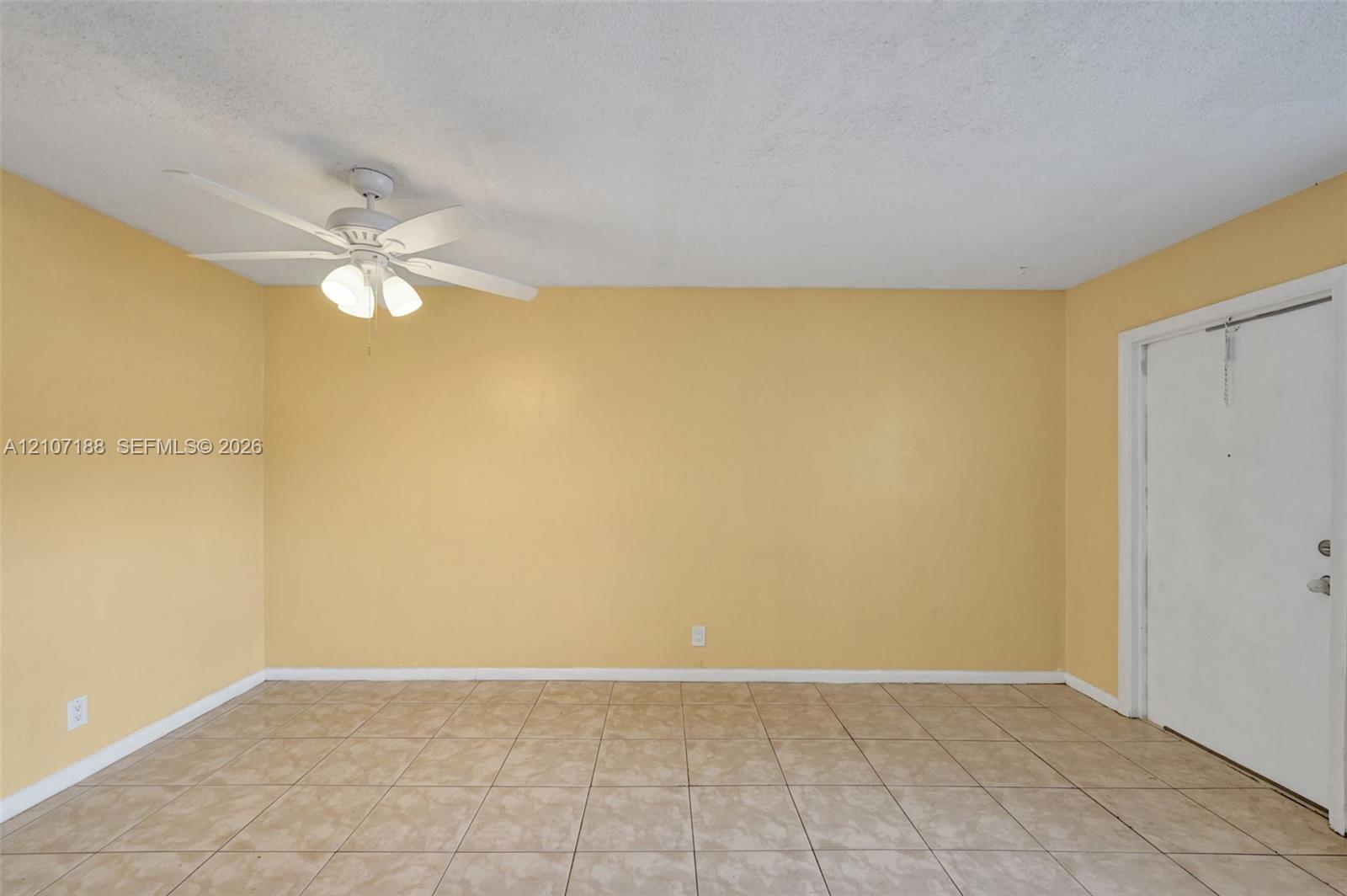 Interior room featuring neutral-toned tile flooring, light-colored wall paint, and a white ceiling fan with integrated lighting